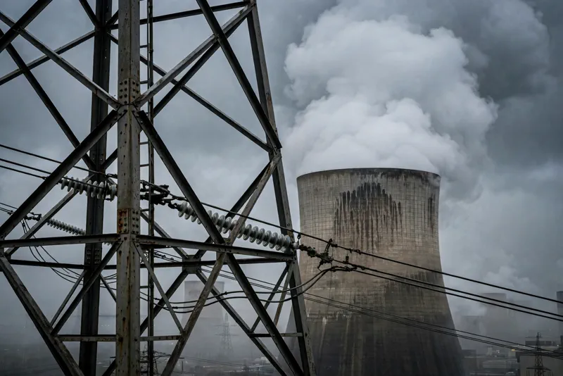 Nuclear power plant cooling tower releasing steam against a moody sky