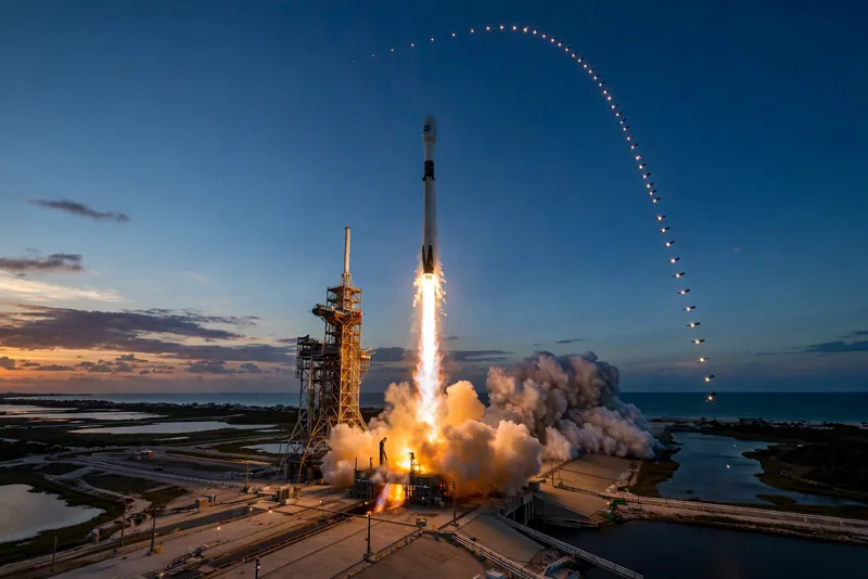 SpaceX Falcon 9 rocket launching at dusk with Starlink satellites in the sky
