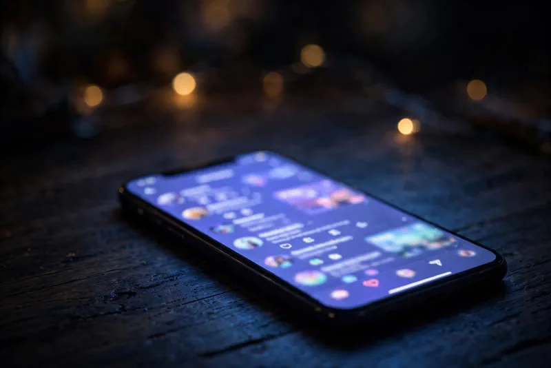 Smartphone on a dark desk with a bright screen, symbolizing Hila Klein's Instagram statement